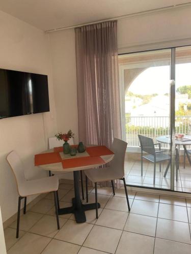 une salle à manger avec une table et des chaises et un balcon dans l'établissement Studio 4 personnes bord de mer avec piscine wifi, à Cervione