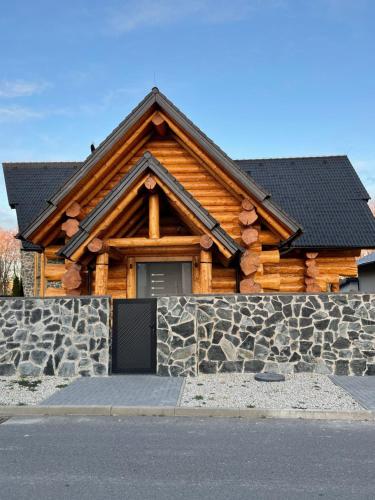 uma cabana de madeira com uma parede de pedra e uma porta em Zrub Mrázik em Veľká Lomnica