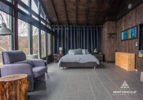 sypialnia z łóżkiem, kanapą i oknami w obiekcie Villa Mont Chocolat w mieście Saint-Philémon