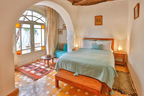 a bedroom with a bed and an arched window at Chems Bleu in Essaouira
