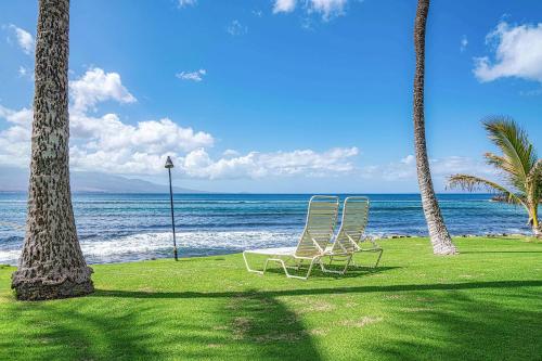 two chairs and two palm trees on the beach at Maalaea Kai 311 - Direct Ocean Front, Split AC in Wailuku