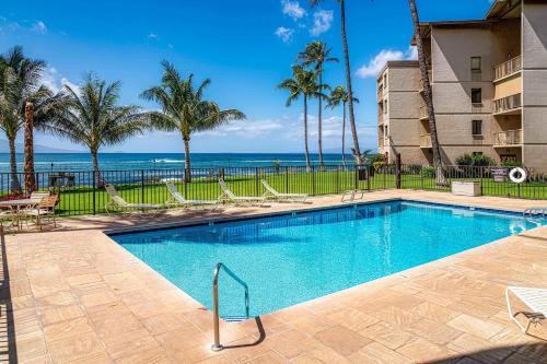 a swimming pool with chairs and the ocean in the background at Maalaea Kai 311 - Direct Ocean Front, Split AC in Wailuku