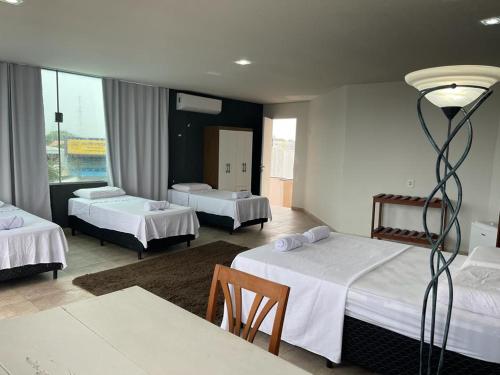 Habitación de hotel con 3 camas y mesa en Hostel e Pousada do Bosque, en Rio Branco