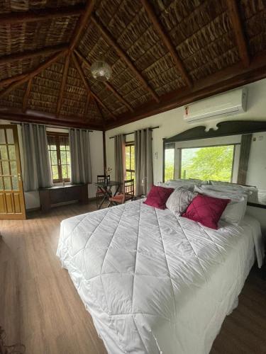 1 dormitorio con 1 cama blanca grande con almohadas rojas en Cinque Terre Pousada & Bistrô, en Río de Janeiro