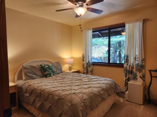 a bedroom with a bed with a ceiling fan and a window at Hale Mauna Loa Upper Level with shared Hot Tub in Volcano