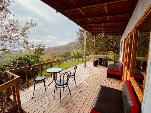 una terraza de madera con mesa y sillas. en Casa Monte Armadillo, en Poás