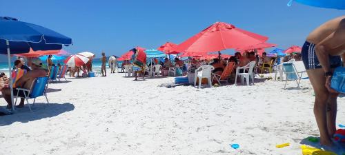 a group of people sitting on the beach under umbrellas at MANDAI Apartamento Cabo Frio in Cabo Frio