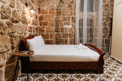 a bed in a room with a stone wall at Hebi house in ‘Akko