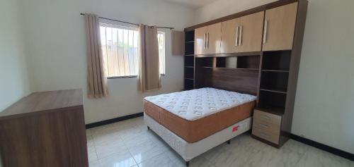 um pequeno quarto com uma cama e uma cómoda em Casa Temporada Praiano em Guriri