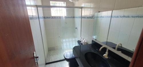 a bathroom with a sink and a toilet and a mirror at Casa Temporada Praiano in Guriri