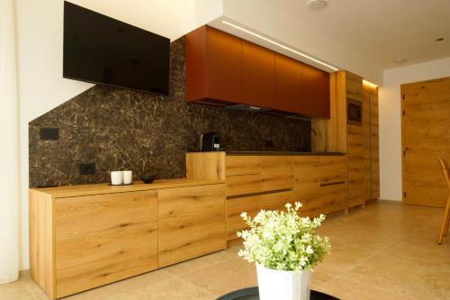 a kitchen with wooden cabinets and a tv on the wall at Chalet Larix Andalo Deluxe Apartments in Andalo