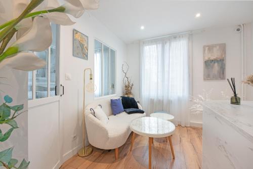 a white living room with a chair and a table at Le Sapphire in Toulouse