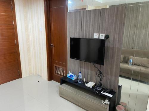 een hotelkamer met een flatscreen-tv aan de muur bij Vittoria Apartment Residence in Jakarta