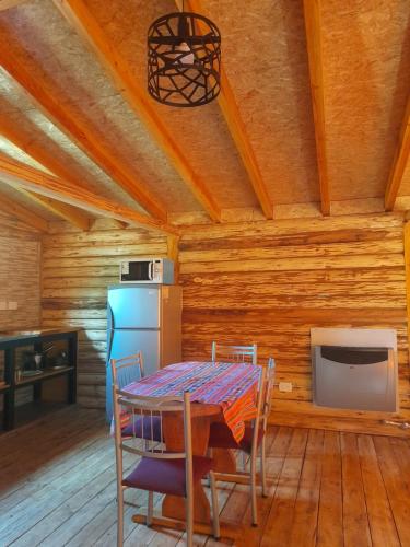 Una cocina con mesa y sillas y un refrigerador. en Cabaña Camila, en El Bolsón