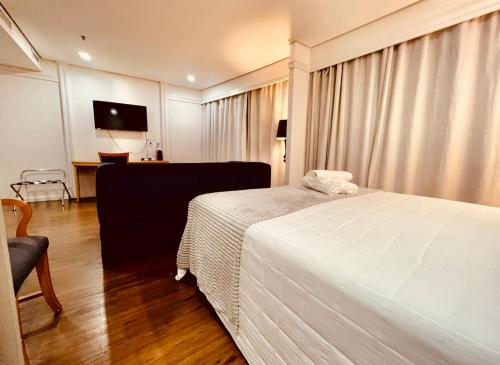 a bedroom with a white bed and a chair at Vila Olimpia Suíte Inside Radisson Hotel in São Paulo