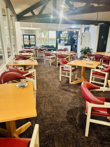 a restaurant with wooden tables and red chairs at Econo Lodge Gateway Tamworth in Tamworth