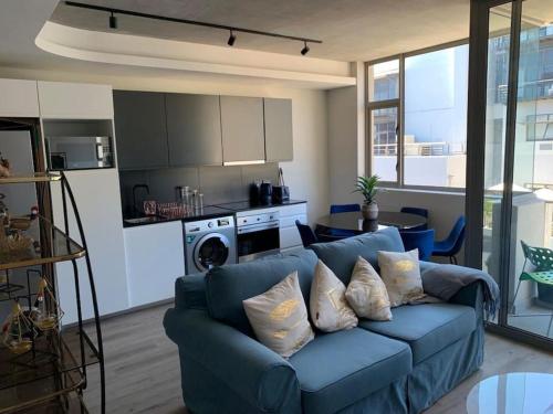 a living room with a blue couch and a kitchen at The Quarter Mountain View Haven at Waterkant in Cape Town
