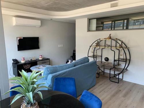 uma sala de estar com um sofá azul e uma televisão em The Quarter Mountain View Haven at Waterkant em Cidade do Cabo