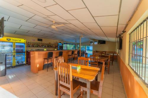 a restaurant with wooden tables and chairs and a bar at Hotel El Cocobolo Food&Rest Room 4 B&B WiFi AC Pkg Free Swimmingpool in Liberia