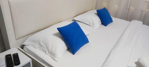 two blue pillows on a white bed in a room at Апартаменты в центре города in Aktobe