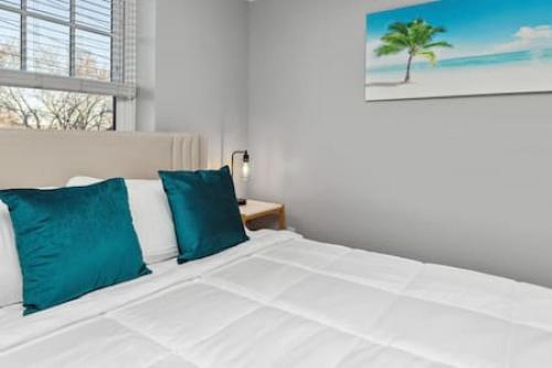 1 dormitorio con cama blanca y almohadas azules en Your Cozy 2-Bedroom Midtown, en Detroit
