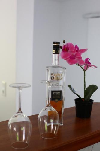 uma garrafa de álcool ao lado de dois copos numa mesa em Villa les MAHOGANYS em Rivière-Salée