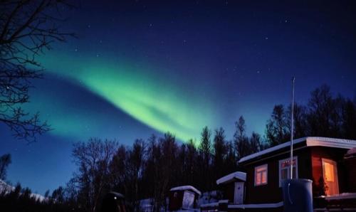 Eine Aurora am Himmel neben einem Haus in der Unterkunft Cozy and spacious cabin in Svensby