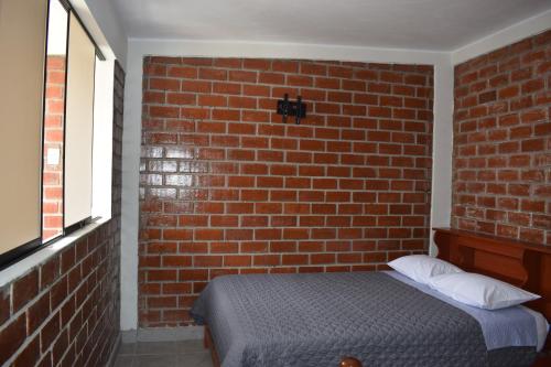 Un dormitorio con una pared de ladrillo y una cama en El Valle Lunahuaná, en Lunahuaná