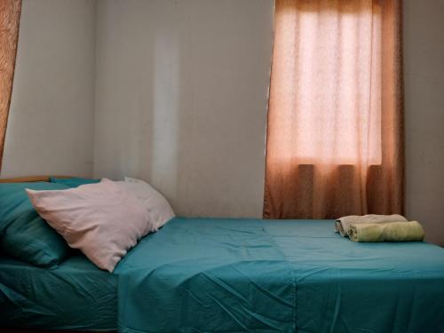 a bed with two pillows on it in front of a window at Eurie's Furnished Unit in Butuan