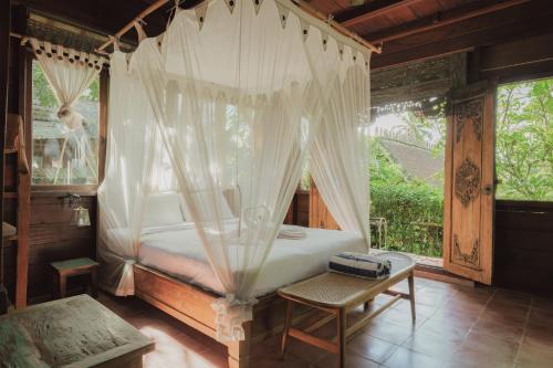 een slaapkamer met een hemelbed en een tafel bij Villa Lumbung in Ubud