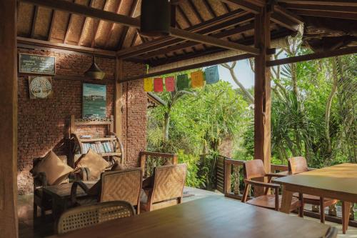 a dining room with tables and chairs and trees at Villa Lumbung in Ubud