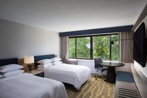 Habitación de hotel con 2 camas y escritorio en Portland Sheraton at Sable Oaks en South Portland