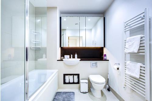 a bathroom with a sink and a toilet and a tub at Luxee Apartment by Excel in London