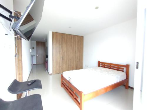 1 dormitorio con 1 cama, TV y silla en Acogedor Apartaestudio Trento 21 Ciudad Jardín Popayan, en Popayán