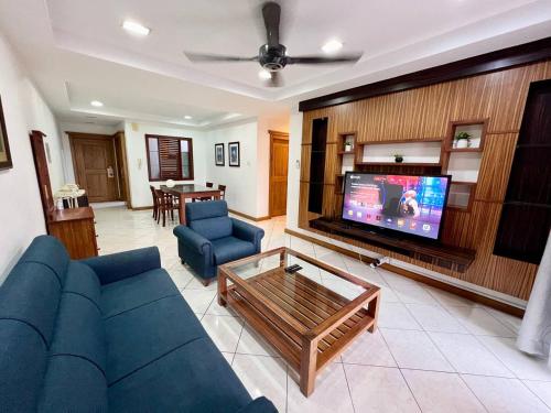 sala de estar con sofá azul y TV en MARINA COURT VACATION HOME 3 BEDROOMS - Kota Kinabalu, en Kota Kinabalu