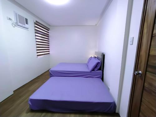 2 bedden in een kleine kamer met paarse lakens bij Casa Maris in Bacoor