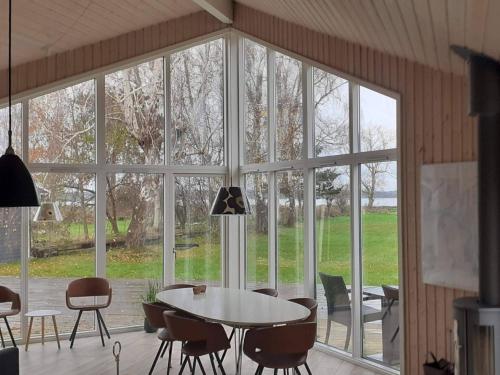 Cette chambre dispose d'une grande fenêtre et d'une table avec des chaises. dans l'établissement Holiday home Jægerspris III, à Jægerspris