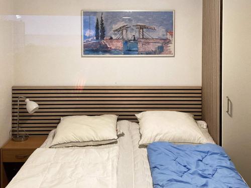 uma cama com duas almofadas e uma fotografia na parede em Holiday home Esbjerg V XI em Esbjerg