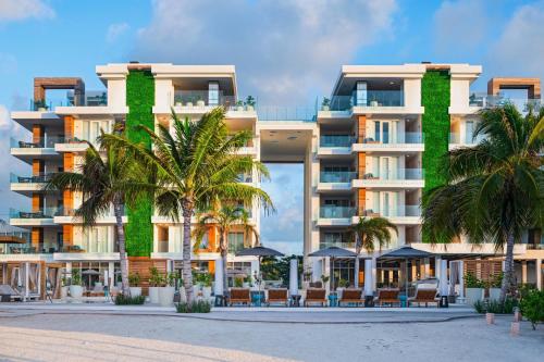 a large apartment building with palm trees and chairs at Alaia Belize, Autograph Collection in San Pedro