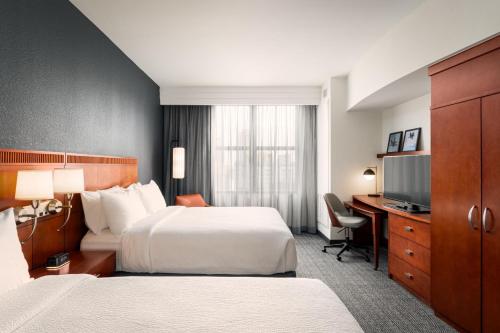 a hotel room with two beds and a desk at Courtyard by Marriott St. Petersburg Downtown in St. Petersburg