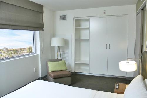 a bedroom with a bed and a chair and a window at Element Miami Doral in Miami