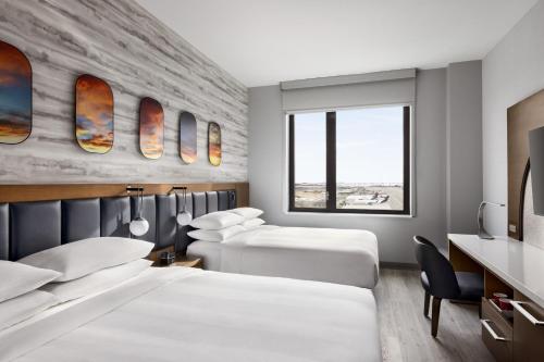 クイーンズにあるMarriott New York JFK Airportのベッド2台と机があるホテルの部屋