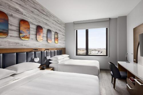 a hotel room with two beds and a desk at Marriott New York JFK Airport in Queens