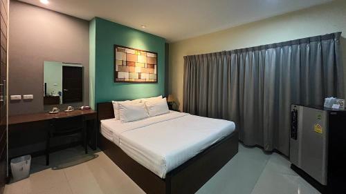 een slaapkamer met een bed en een bureau met een spiegel bij Ma Chic & Cozy in Lampang