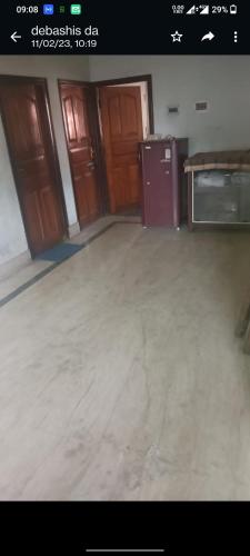 una imagen de una habitación con puertas de madera y suelo en Anjan Home Stay en Durgāpur