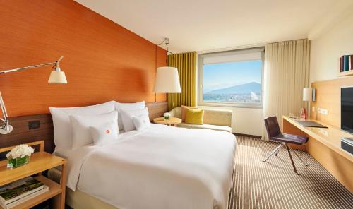 a hotel room with a large white bed and a window at InterContinental Genève by IHG in Geneva