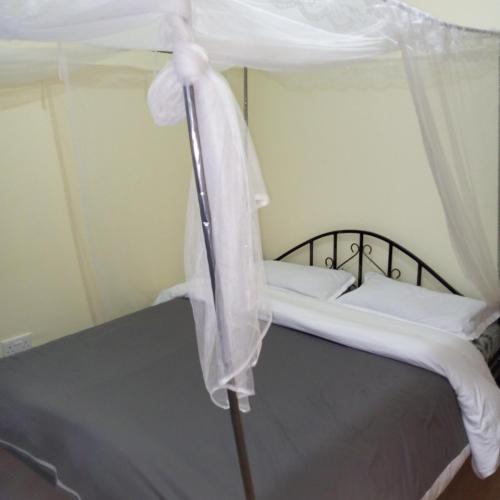 1 cama con dosel en una habitación en Miller's Haven, en Kakamega