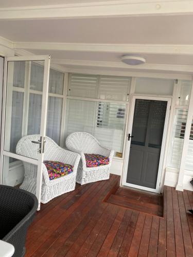 a porch with two wicker chairs and a door at Plantation House Bathurst 109Mitre in Bathurst