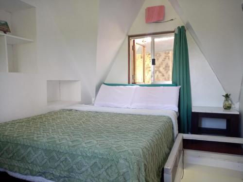 a small bedroom with a bed and a window at Bulkan Villa Rental in General Luna