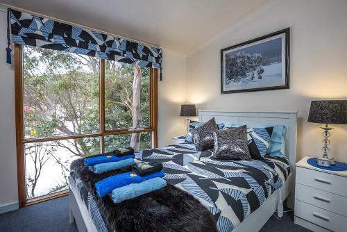a bedroom with a bed and a large window at Tanjil Creek Lodge in Baw Baw Village